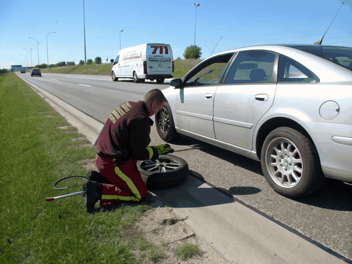 Technician changing a flat tire on a roadside service van